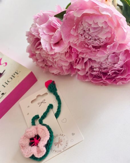 A pink flower bookmark beside a pink peony on an open book.