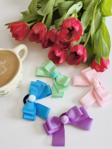 Handmade hair-ties bows set featuring blue, mint green, pink and lavender double-layered bows, with a small, fluffy accessory in the center.