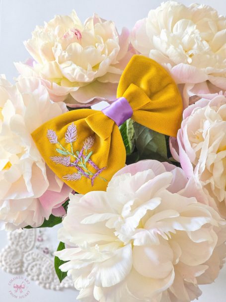 Yellow velvet bow with lilac Gemini symbol and lavender embroidered and soft lilac center.