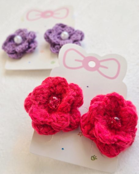 Set of two crochet red flower hair ties with pearls in the center.