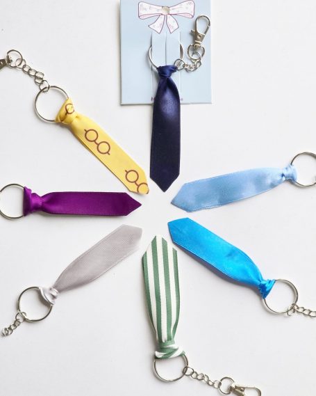 A collection of seven keyrings shaped like ties in various colours on a card.