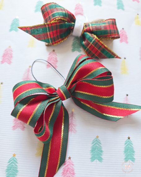 Two festive bows, one green and red plaid, the other green with red stripes, on a patterned background.