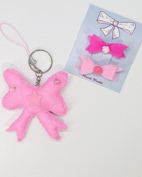 A pink bow keychain next to two pink and white decorative bow clips.