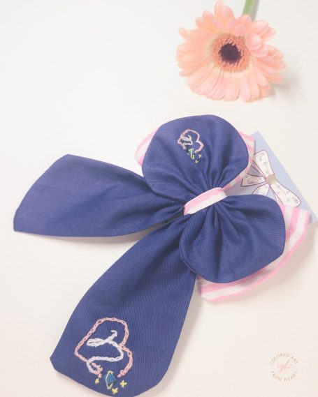Navy blue zodiac-inspired signature bow featuring embroidered Capricorn constellation and celestial details.