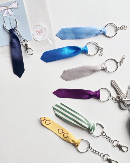 A collection of seven keyrings shaped like ties in various colours on a card.