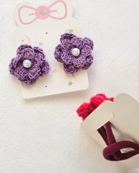Set of two crochet purple flower hair ties with pearls in the center.