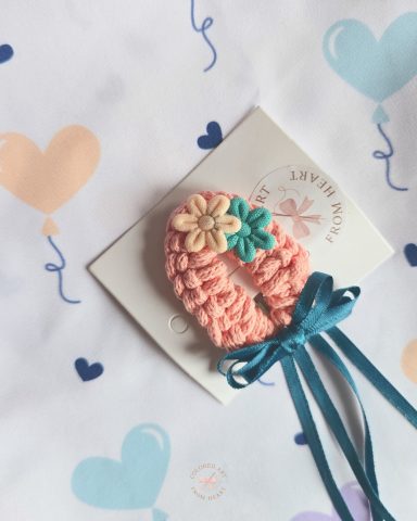 Cindy Hair Clip A soft peach shade hair accessory adorned with flowers and a teal ribbon