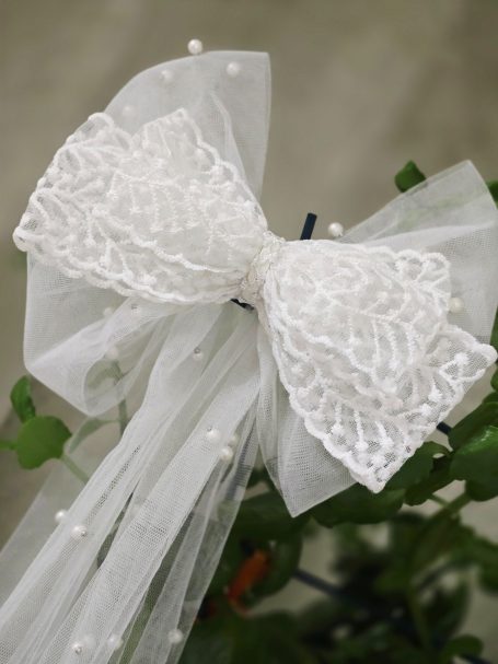 Elegant white bridal bow with long flowing tails and attached pearls, designed as a timeless wedding hair accesory.