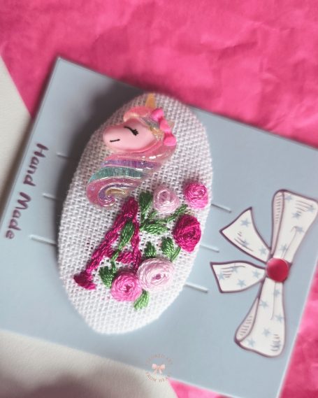 Handmade personalised hair clip featuring a small applied unicorn figurine and the letter A, surrounded by small roses, all embroidered