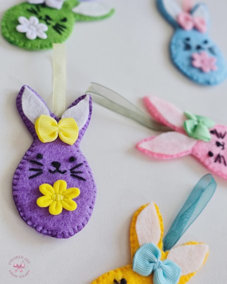 Collection of five colourful felt bunny charms in pastel colours with bows and floral details.
