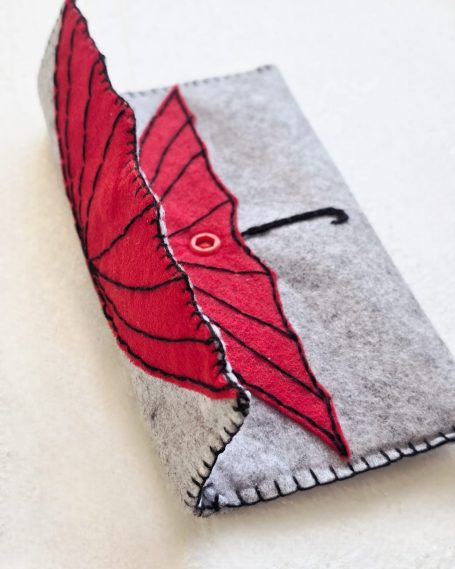 Grey pouch with a red umbrella design on the front.
