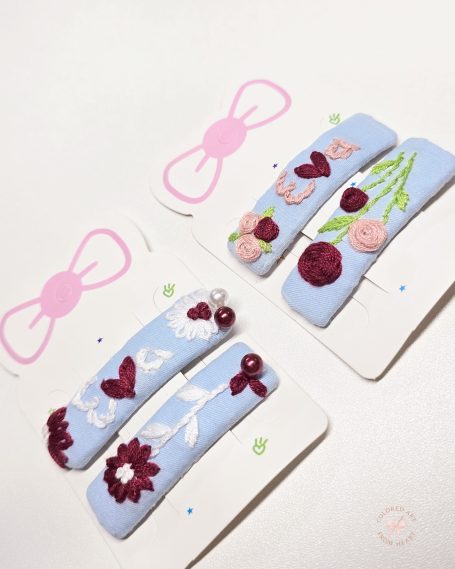 Handmade personalised embroidered hair clip set, featuring floral designs, hearts and the name "Eva".
