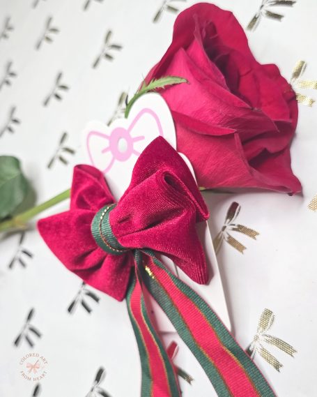 Deep red velvet bow with long, green tails, inspired by classic romantic elegance.
