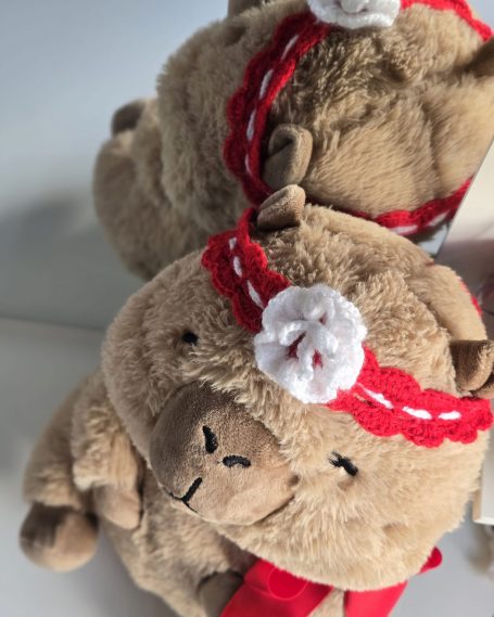 Stuffed bear wearing a red headband with a white flower decoration.