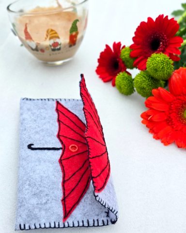 Under the Red Umbrella - Felt Pouch Grey pouch with a red umbrella design on the front.