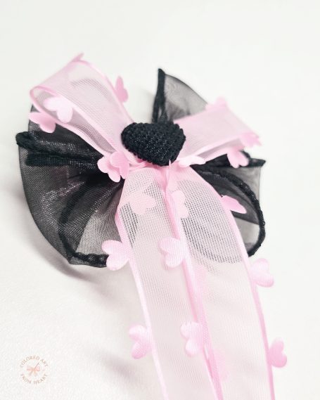 Handmade black and pink statement hair bow with layered ribbons and flowing tails with hearts details.