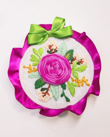 Positive Rose – Decoration Embroidered floral design featuring a pink rose and green leaves, adorned with a ribbon.