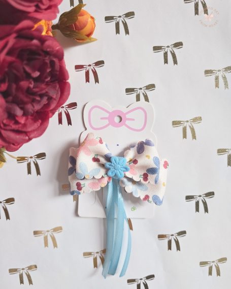A handmade hair clip in soft shades of blue, white and pink. Soft textures and flowing blue ribbons.