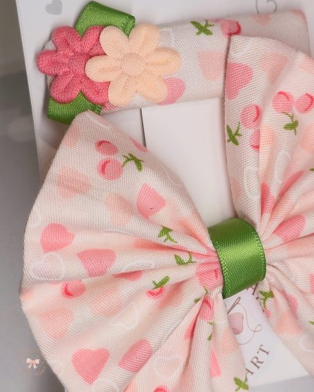 Set featuring a statement butterfly- bow and a matching clip. Soft pink fabric with hearts and cherry prints and a fresh touch of green.