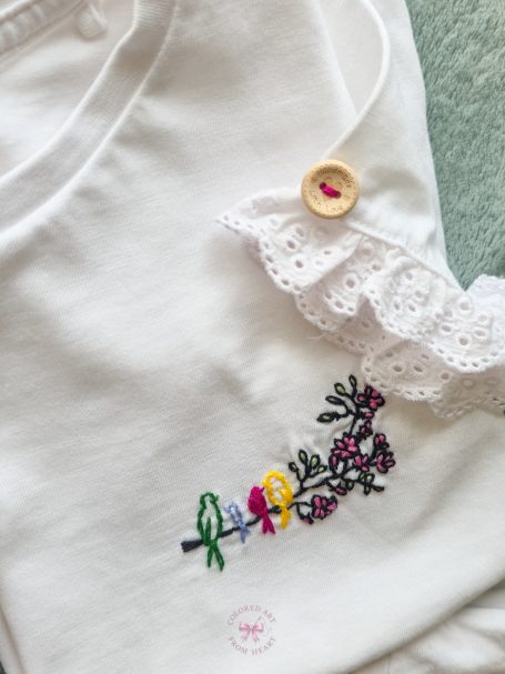 White T-shirt with birds embroidery and a decorative lace trim featuring a wooden button.
