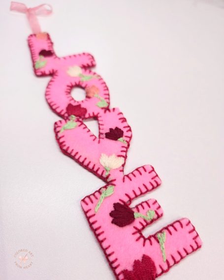 Pink felt bookmark spelling "love", with floral embroidery.