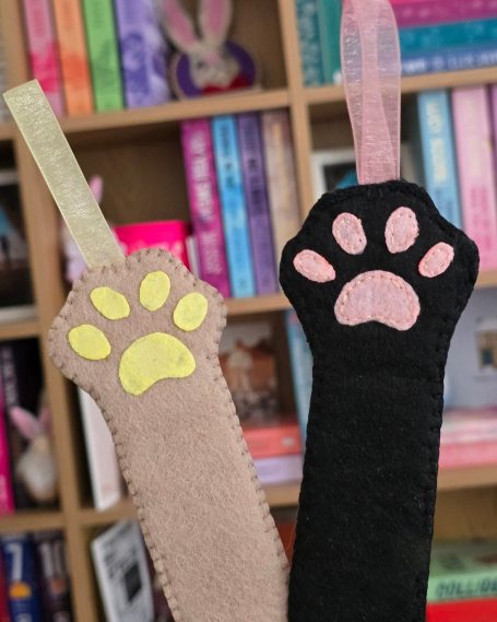 Two felt bookmarks designed as animal paws in beige and black.