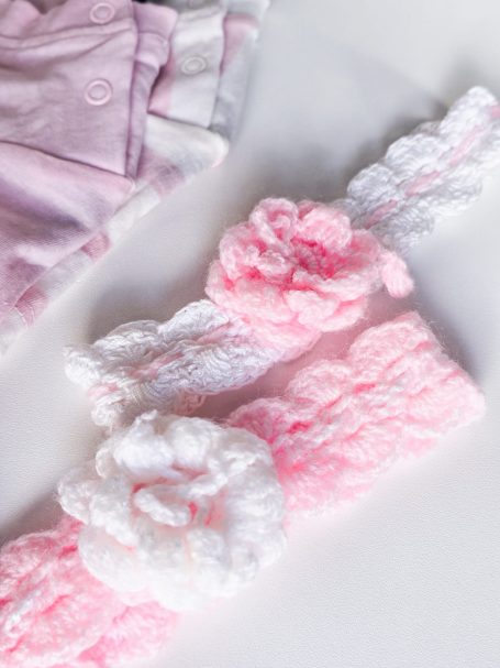 Two decorative hairbands in pink and white, featuring floral designs.