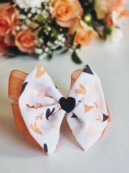 White and orange zodiac-inspired signature bow featuring embroidered Aries symbol and delicate hearts details.
