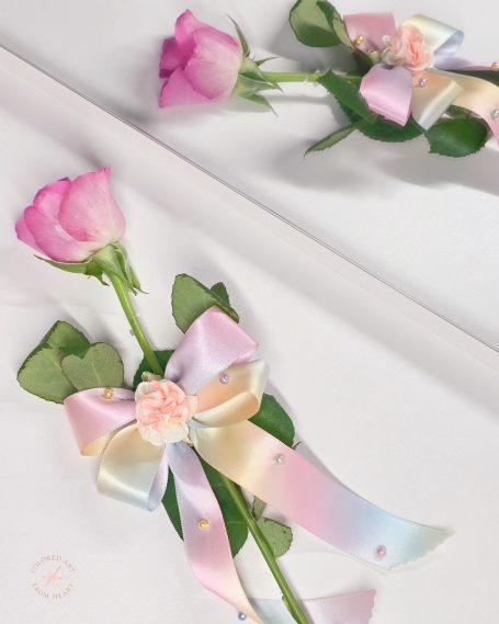 Pastel rainbow bow with attached pearls and delicate floral detail in the center.
