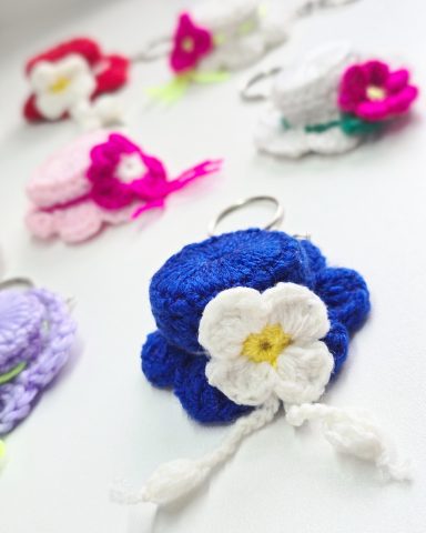 Hat in Hand - Crocheted Keychain/ Bag Charm Colourful crocheted keychains in various shapes, featuring hats with flowers and decorative details.