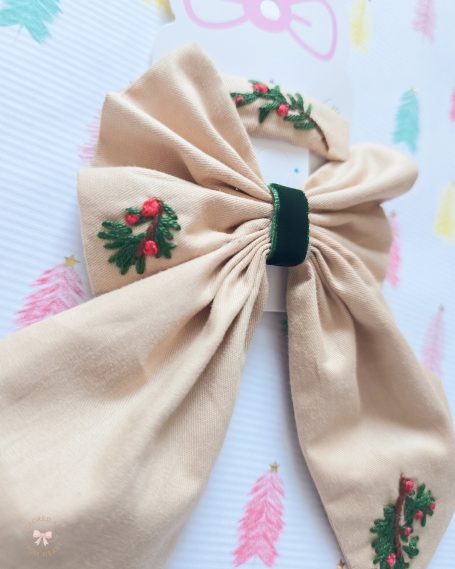 Champagne Christmas bow embroidered with festive mistletoe details and matching hair clip.