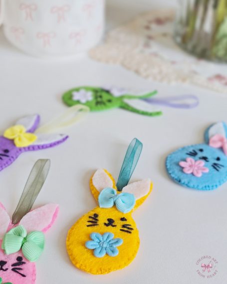 Collection of five colourful felt bunny charms in pastel colours with bows and floral details.